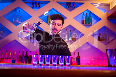 Bartender pouring alcohol in shot glasses