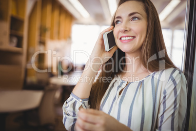 Happy businesswoman using mobile phone in office cafeteria