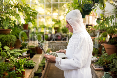 Male scientist in clean suit using laptop