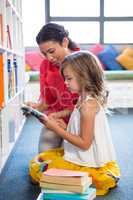 Teacher assisting girl searching book in library