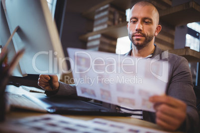 Businessman looking at photographs while using graphics tablet