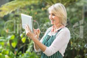 Mature female gardener using digital tablet