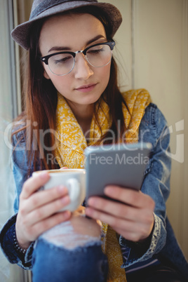 Fashionable woman using mobile phone at cafeteria