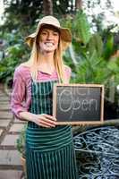 Portrait of beautiful gardener with open text on chalkboard at g