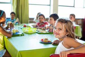 Cute girl with classmates having meal