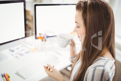 Businesswoman having coffee while working in creative office