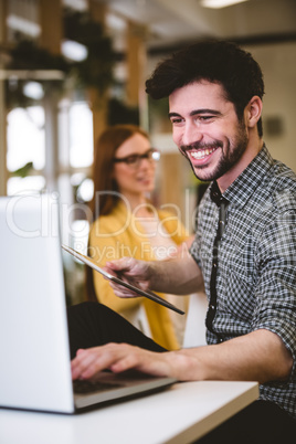 Happy businessman using laptop with female coworker