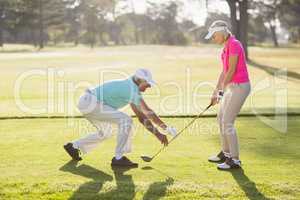 Mature male teaching woman to play golf