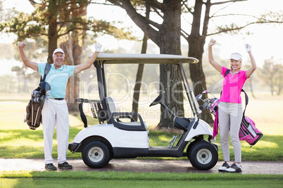 Portrait of smiling mature golfer couple with arms raised