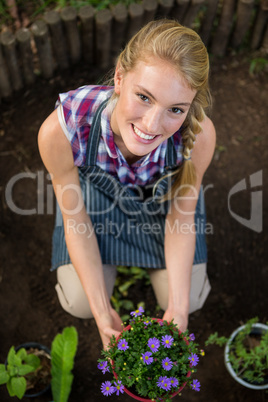 Portrait of beautiful gardener with potted plant at garden