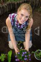 Portrait of beautiful gardener with potted plant at garden