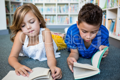 Girl and boy reading books at library in school