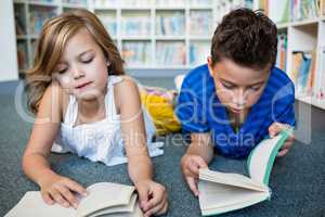 Girl and boy reading books at library in school