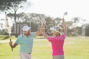 Cheerful mature golfer couple giving high five