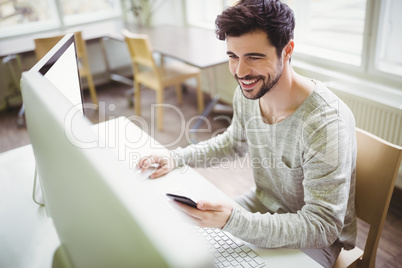 Smiling businessman using mobile phone in office