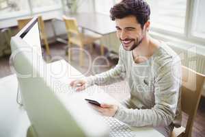 Smiling businessman using mobile phone in office