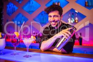 Bartender smiling while holding cocktail shaker