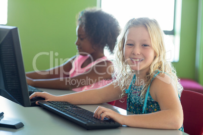Happy girl with classmate using computers