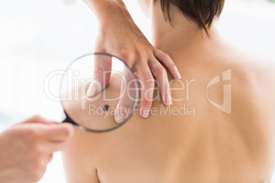 Cropped image of doctor examining patient back with magnifying g