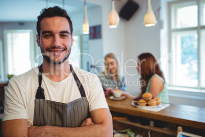 Portrait of happy barista with arms crossed at coffee shop