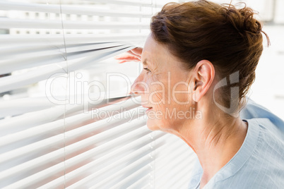 Mature woman looking through blinds