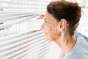 Mature woman looking through blinds