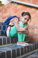 Girl sitting on steps at corridor in school