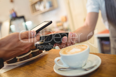 Close-up of customer with cellphone and barista with card reader