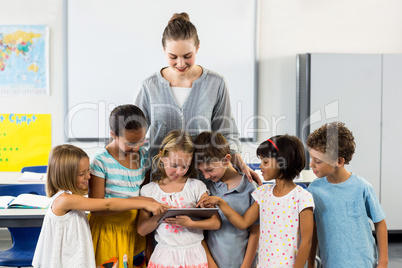 Teacher looking at schoolchildren using digital tablet