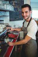 Portrait of confident barista using espresso maker at cafeteria