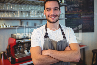 Portrait of confident waiter with arms crossed at cafe