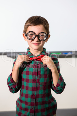 Boy tying bow while standing in classroom