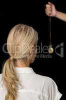 Cropped hand of hypnotherapist holding pendulum by woman