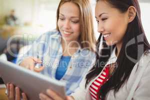 Smiling female colleagues with digital tablet in creative office