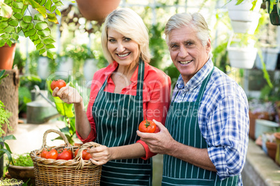 Portrait of couple with tomatoes at greenhouse