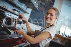 Portrait of happy barista using espresso maker at cafe