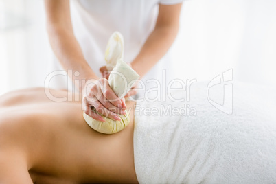 Masseur giving herbal compress massage to woman