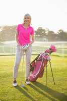 Woman golfer posing with her golf equipments