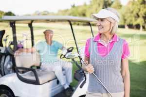 Happy mature woman holding golf club