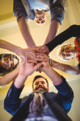 Happy business people stacking hands in creative office