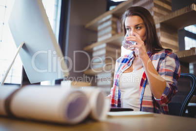 Businesswoman looking at computer while drinking water