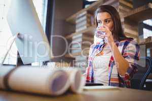 Businesswoman looking at computer while drinking water