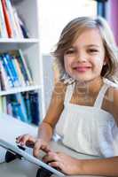 Smiling girl using digital tablet in school library