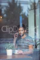 Handsome man talking on cellphone at cafe