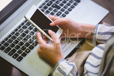 Midsection of executive using cellphone over laptop at office Midsection of executive using cellphone over laptop at office