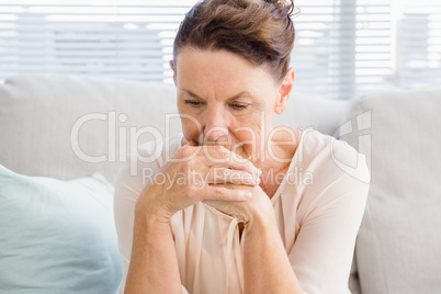 Sad mature woman sitting on sofa