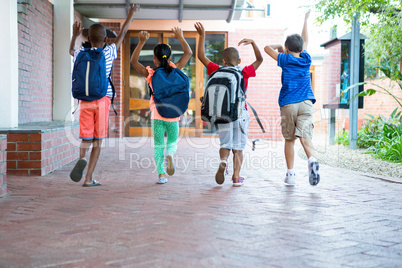 Rear view of classmates running at school corridor