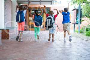 Rear view of classmates running at school corridor