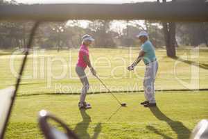 Mature man teaching woman to play golf