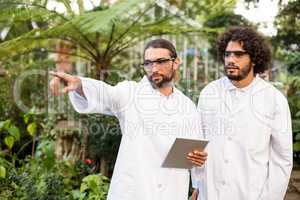 Male scientist pointing while standing by coworker